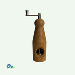 Eine Muskatmühle aus mittelbraunem Holz mit einer Kurbel oben. Das Bild zeigt die Mühle von der anderen Seite mit dem Loch, in das die Muskatnuss eingelegt und in das Mahlwerk eingeklemmt wird.