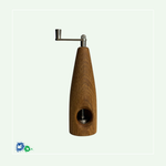 Eine Muskatmühle aus mittelbraunem Holz mit einer Kurbel oben. Das Bild zeigt die Mühle von der anderen Seite mit dem Loch, in das die Muskatnuss eingelegt und in das Mahlwerk eingeklemmt wird.