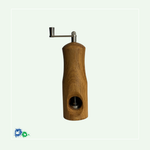 Eine Muskatmühle aus mittelbraunem Holz mit einer Kurbel oben. Das Bild zeigt die Mühle von der anderen Seite mit dem Loch, in das die Muskatnuss eingelegt und in das Mahlwerk eingeklemmt wird.