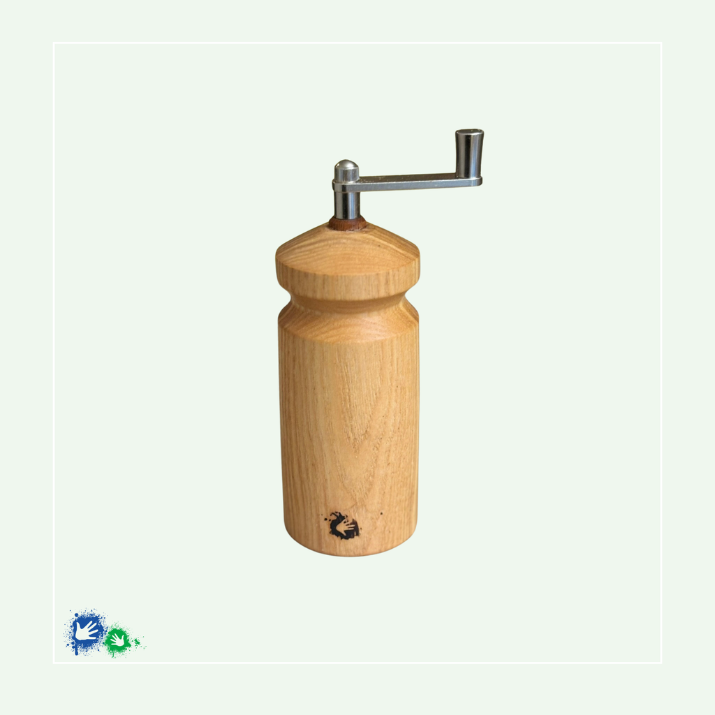 Eine Muskatmühle aus hellem Holz mit einer Kurbel oben. Unten ist ein Hände-Logo eingebrannt.