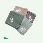 Das Bild zeigt vier zusammengefaltete Mulltücher, die gefächert versetzt übereinander gelegt sind. Die Tücher sind in folgenden Farben: icegreen, mint, beige und taupe. Alle vier Tücher haben einen kleinen weißen Hände-Logo-Aufdruck.